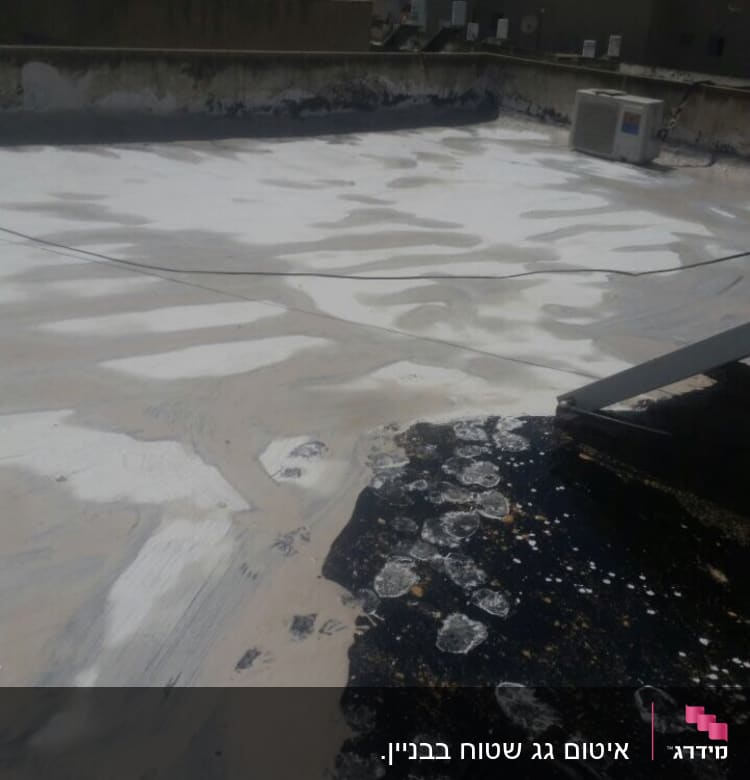 גג עם שכבת איטום לבנה וכתמים כהים